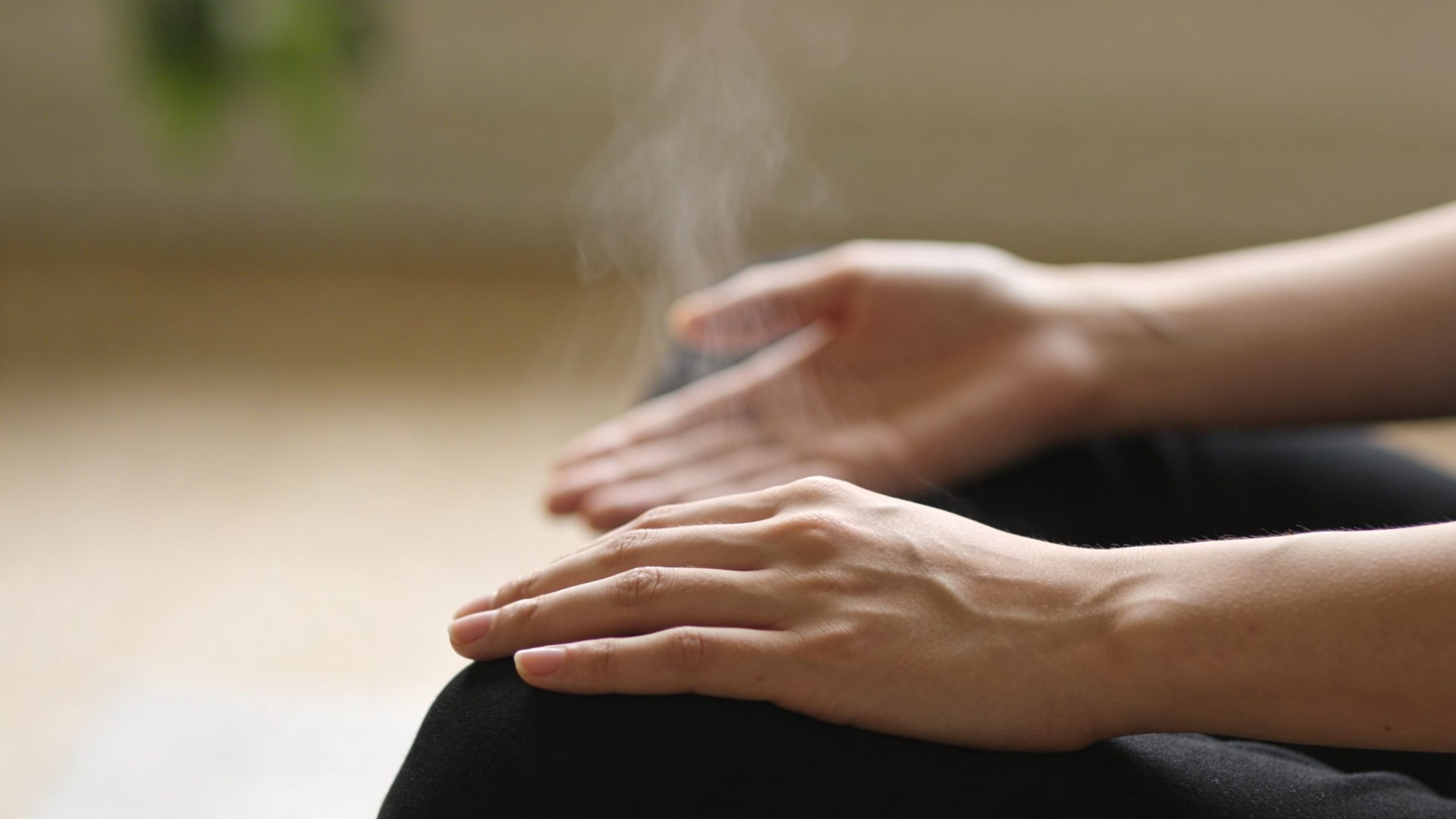 A close-up view of hands resting on knees during a mindful meditation or stress relief exercise session.