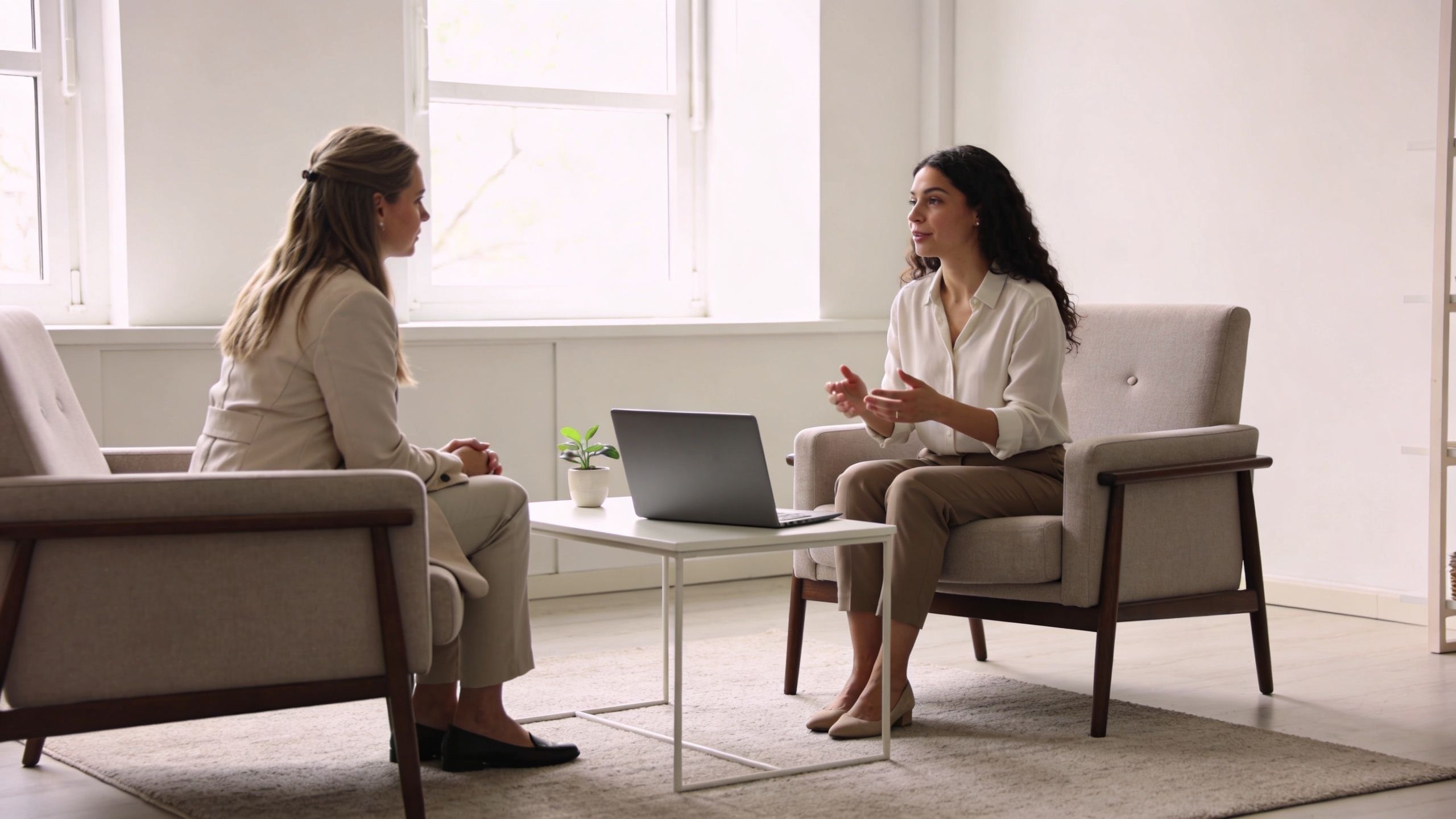 A woman speaks to her therapist during a professional counseling session in a brightly lit office.