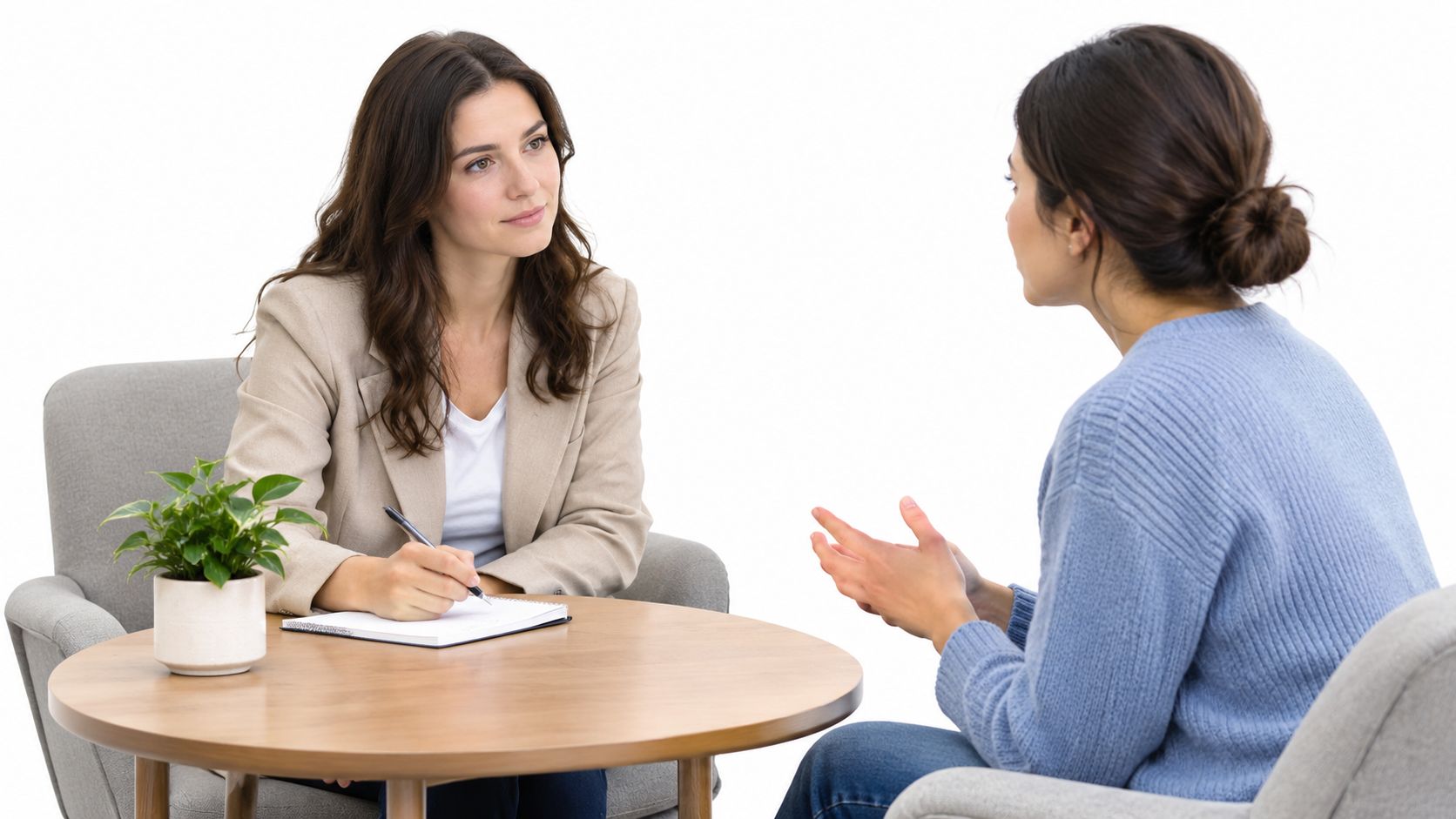 A professional therapist listening carefully while taking notes during a counseling session with a client.